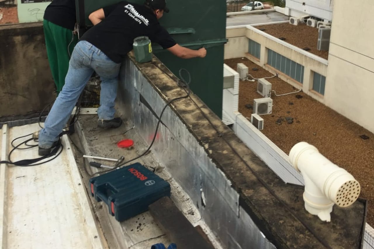 Técnico da Designer Inox instalando sistema de exaustão em cobertura